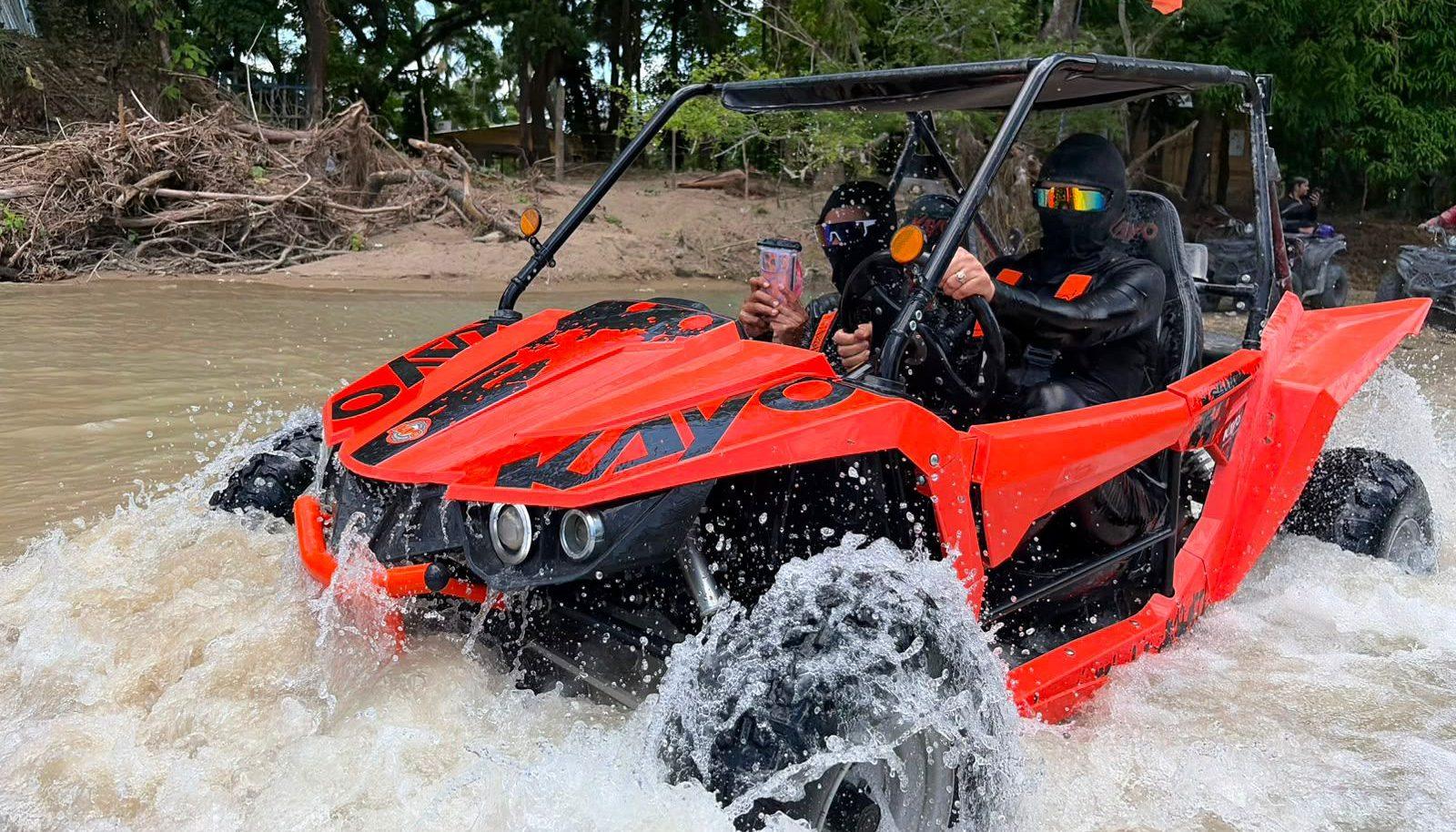 Orange dune buggy splashing through a river crossing
