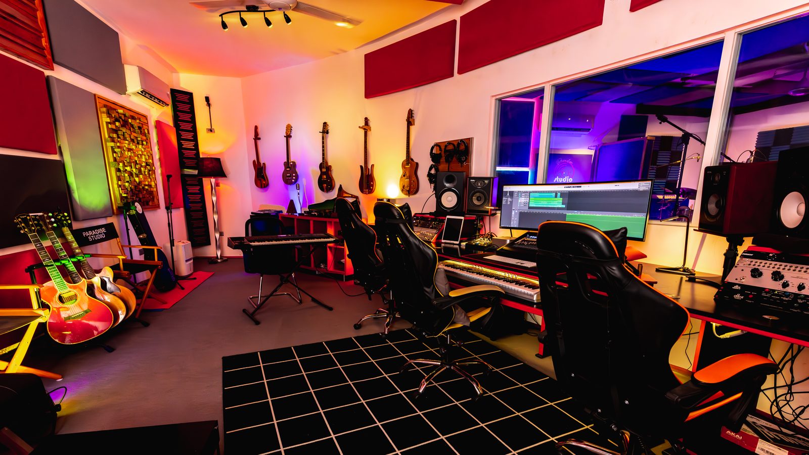 Paradise Studio Red Room — control room with red acoustic panels and guitar wall / Sala roja — sala de control con paneles acústicos rojos y pared de guitarras